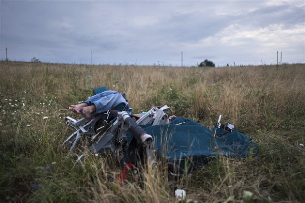 CAPTION CORRECTION, CORRECTS TO IMPROVE SYNTAX AND CLARITY OF CAPTION - The body of a passenger is partially visible as it lies in a chair at the crash site of Malaysia Airlines Flight 17 near the village of Hrabove, eastern Ukraine, Saturday, July 19, 2014. World leaders demanded Friday that pro-Russia rebels who control the eastern Ukraine crash site of Malaysia Airlines Flight 17 give immediate, unfettered access to independent investigators to determine who shot down the plane. (AP Photo/Evgeniy Maloletka)