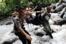 Habitantes y policía indonesia sacan los cuerpos de víctimas de las inundaciones en Sibolangit, en el norte de Sumatra, el 16 de mayo de 2016