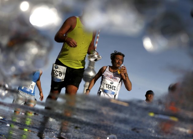Runners are reflected in a puddle as they pass a drinks station in front of the TV Tower during the 41st Berlin marathon September 28, 2014.  Picture rotated 180 degrees.   REUTERS/Thomas Peter (GERMANY  - Tags: SPORT ATHLETICS TPX IMAGES OF THE DAY)