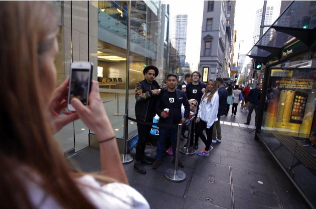Customers take a photograph as they stand in a line outside the Apple store in Sydney on the first day the new iPhone 6 and iPhone 6 Plus went on sale