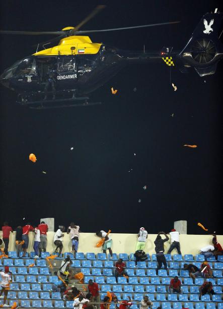 A police helicopter hovers over Equitorial Guinea fans as they throw objects during the African Cup semi-final match against Ghana in Malabo