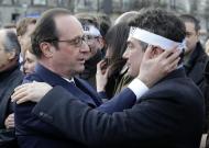 French President Francois Hollande (L) comforts columnist for Charlie Hebdo Patrick Pelloux as they attend the solidarity march in the streets of Paris on January 11, 2015