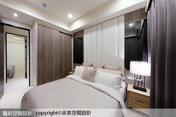 主臥主牆以白色為中心，兩側對稱裝飾深色鏡面，營造安穩的睡眠環境。
