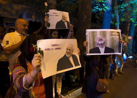 Iranians hold pictures of Iranian Foreign Minister Mohammad Javad Zarif as they celebrate in the street following a nuclear deal with major powers, in Tehran July 14, 2015. REUTERS/TIMA