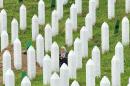 A Bosnian Muslim woman, survivor of the Srebrenica 1995 massacre, searches for remains of her relative among body caskets at a memorial cemetery in the village of Potocarion on July 10, 2014