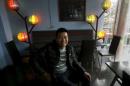 Tran Khanh Sinh, a gay person, poses for a photo in   front of lamps in the colours of the gay rainbow flag at Comga restaurant where he   is working in Hanoi