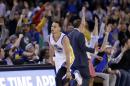 El público reacciona mientras el jugador de los Warriors de Golden State Stephen Curry, en el centro, encesta un triple durante su juego de NBA contra los Hawks de Atlanta en Oakland, California, el 18 de marzo de 2015.(AP Foto/Marcio Jose Sanchez)