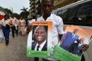 Un homme pose avec des affiches montrant le président Alassane Ouattara à Abidjan, le 25 avril 2015