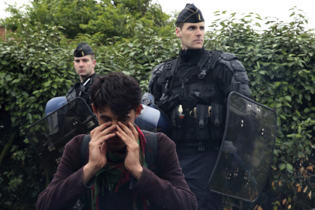 An Afghan immigrant wipes his eyes as police evacuate him and others at an improvised camp in Calais