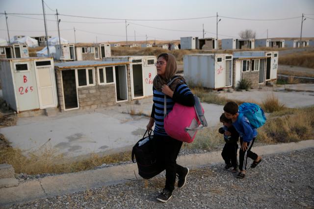 In this Oct. 17, 2019 file photo, Salwa Hanna with her children, who are Christian and newly displaced by the Turkish military operation in northeastern Syria, carry their belongings after they arrive at the Bardarash refugee camp, north of Mosul, Iraq.