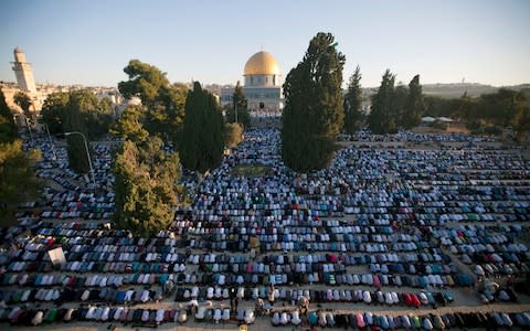 Palestinian Muslim men perform the morning Eid Al-Fitr prayer in front of the Dome of Rock at the Al-Aqsa Mosque compound in 2013 - Credit: AHMAD GHARABLI/AFP/Getty Images