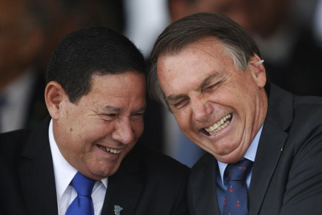 Brazil's President Jair Bolsonaro, right, has a laugh with Vice President Hamilton Mourao, during a military ceremony in honor of Sailor Day, in Brasilia, Brazil, Friday, Dec. 13, 2019. (AP Photo/Eraldo Peres)