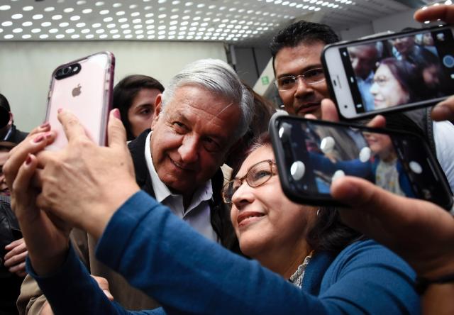 Even aboard a plane, Mexico President Andres Manuel Lopez Obrador takes the time to pose for photos with other passengers, much to the chagrin of flight attendants