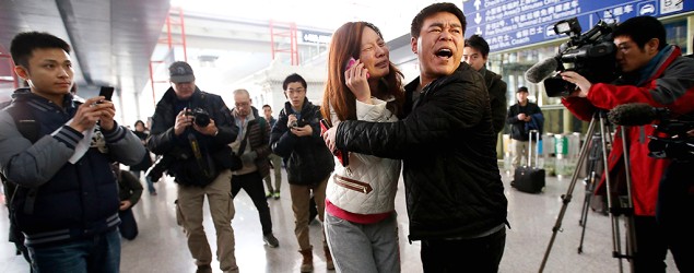 A relative (woman in white) of a passenger onboard Malaysia Airlines flight MH370 cries as she talks on her mobile phone at a Beijing airport. (Reuters)