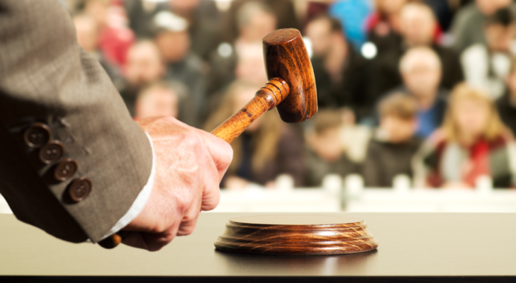 Image of a hand holding a wooden hammer at an auction.