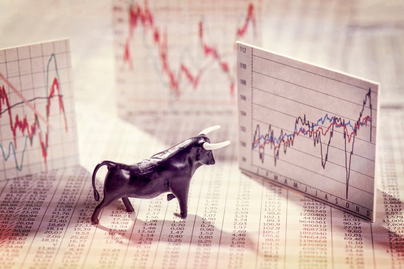 A bull figurine looking at a stock chart.